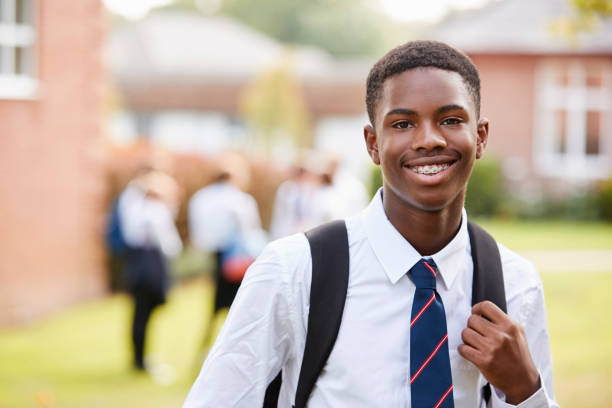 portrait of male teenage student in uniform outside buildings